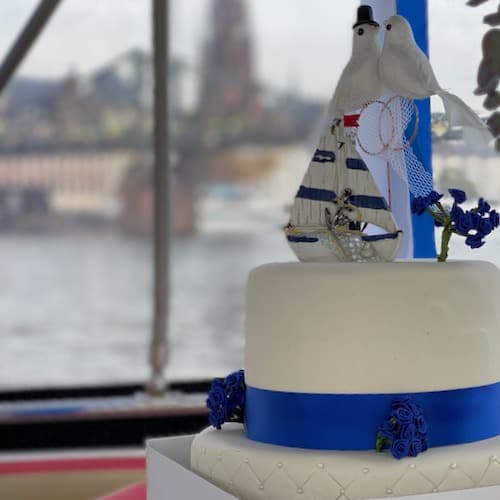 Hochzeitstorte auf einem Boot mit Marine Dekoration. Im Hintergrund Kaiserdom und Eiserner Steg Frankfurt