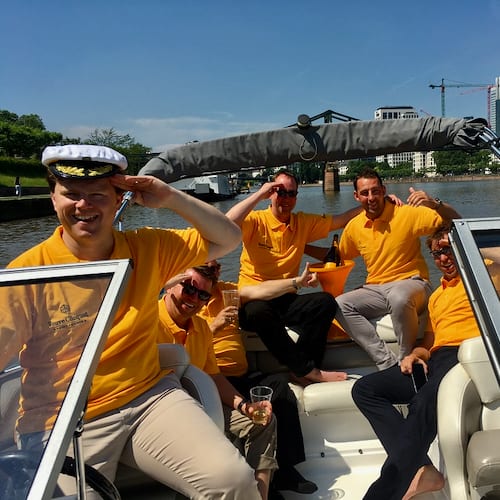 Arbeitskollegen mit Organgen Poloshirts der Firma auf einem Boot während einer Incentive Reise in Frankfurt