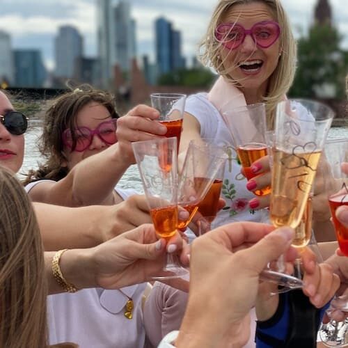 Frauen mit Kunststoff Sektgläser beim feiern auf dem Partyboot mit der Skyline Frankfurt im Hintergrund