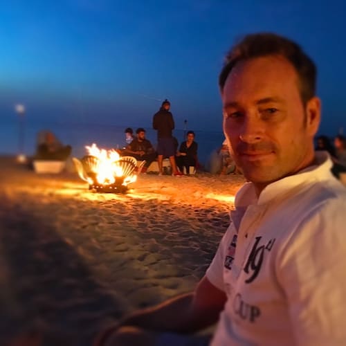 Romantisches Lagerfeuer am Strand in einer lauen Sommernacht mit Freunden