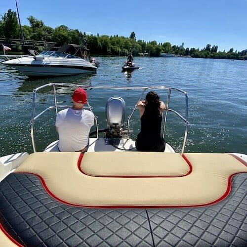 Gäste an Bord des Partyboot die bei Sommerhitze die Beine ins Wasser baumeln lassen und auf der Aussenterasse des Boot sitzen